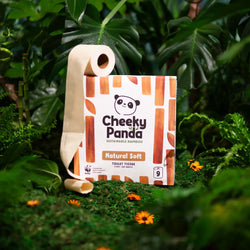 Cheeky Panda unbleached sustainable bamboo toilet tissue package in a natural setting with green leaves and flowers.
