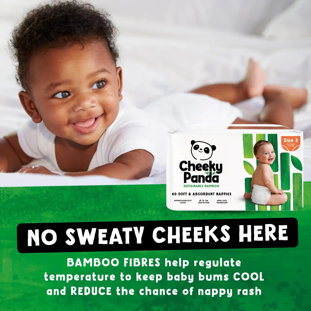Baby lying on a white blanket with Cheeky Panda bamboo diapers packaging displayed.