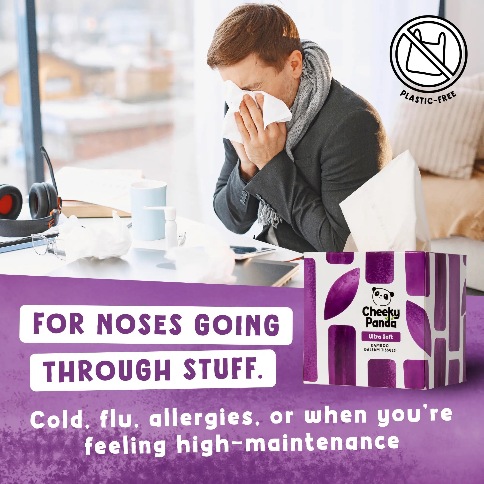 A man blowing his nose with a Cheeky Panda tissue, with a purple tissue box in the foreground.
