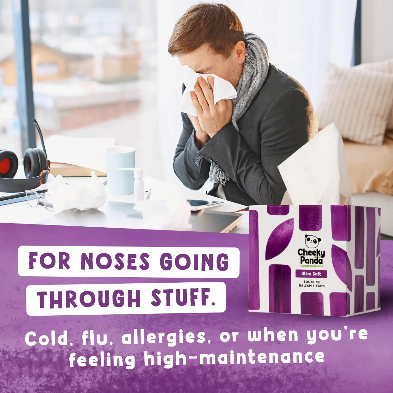 Person with a cold, sneezing into a tissue, with a box of Cheeky Panda tissues in the foreground.