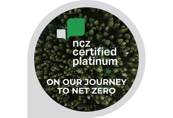  A circular badge or sticker featuring an aerial view of dense green trees, with white text reading 'ncz certified platinum' and 'ON OUR JOURNEY TO NET ZERO.' A green and white logo appears near the top. 