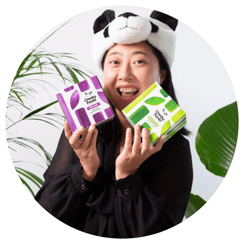  Person wearing a panda headband holding two boxes with green and purple designs against a white background. 